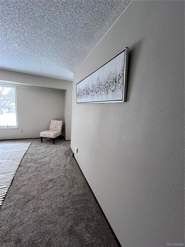 carpeted empty room featuring a textured ceiling and a textured wall