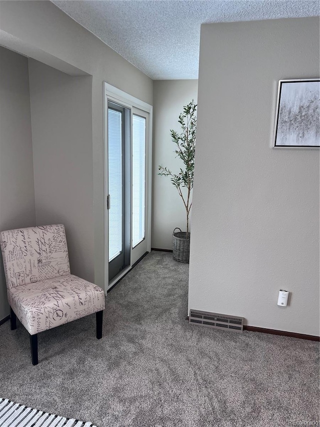 living area featuring baseboards, visible vents, a textured ceiling, and carpet flooring