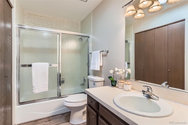 full bathroom featuring toilet, enclosed tub / shower combo, wood finished floors, and vanity