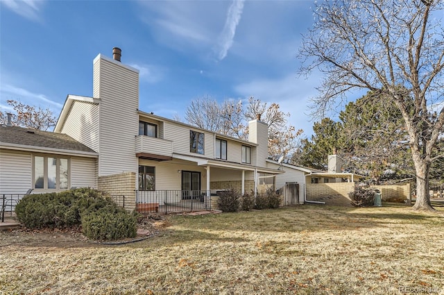 rear view of property with a chimney and a lawn