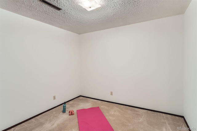 unfurnished room with a textured ceiling, baseboards, visible vents, and light colored carpet