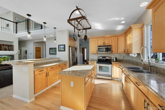 kitchen featuring stainless steel appliances, sink, a kitchen island, and light hardwood / wood-style flooring