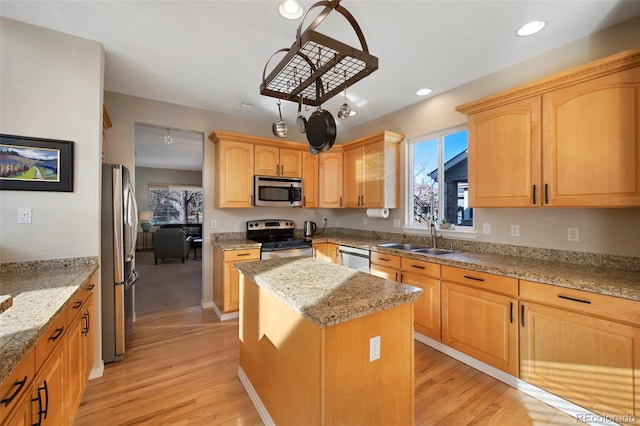 kitchen featuring light stone counters, appliances with stainless steel finishes, sink, and a kitchen island