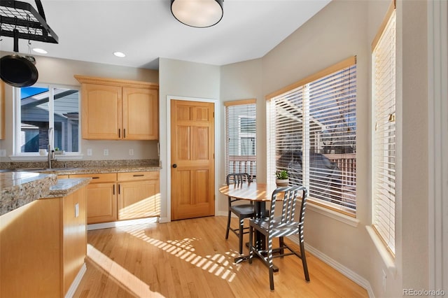 kitchen with light brown cabinetry, light stone counters, and light hardwood / wood-style floors