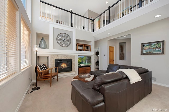 carpeted living room featuring stacked washer and dryer, a high ceiling, and built in shelves