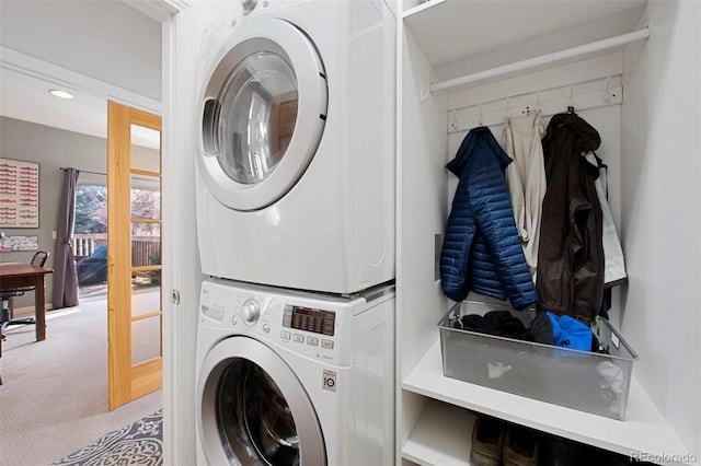 clothes washing area with stacked washing maching and dryer and light colored carpet