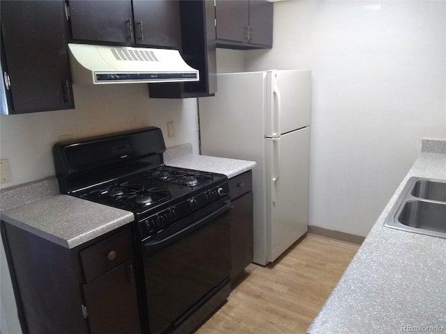 kitchen with ventilation hood, gas stove, light wood finished floors, freestanding refrigerator, and a sink