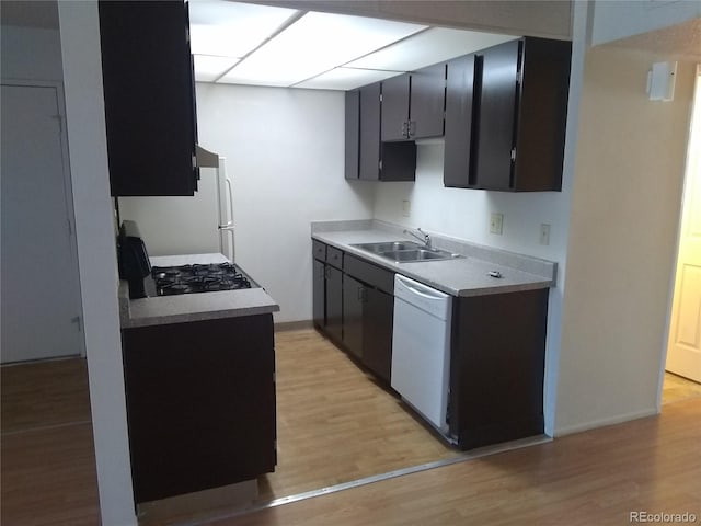 kitchen with white appliances, a sink, light wood-style floors, light countertops, and baseboards
