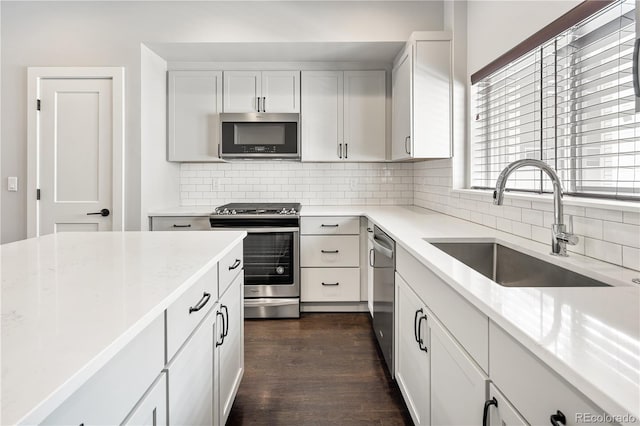 3820 N Olive St Unit 2, Denver, CO 80207 - kitchen with appliances with stainless steel finishes, backsplash, dark wood finished floors, white cabinets, and light stone countertops