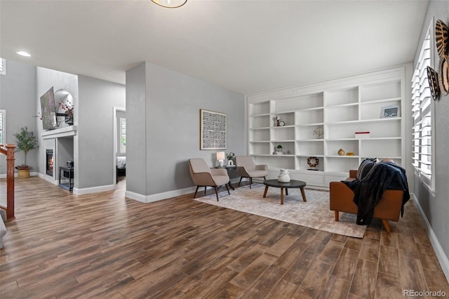 24682 E Ontario Dr, Aurora, CO 80016 - living area featuring dark wood-type flooring, baseboards, a lit fireplace, built in shelves, and recessed lighting