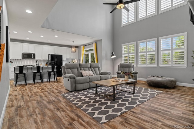 24682 E Ontario Dr, Aurora, CO 80016 - living area featuring wood finished floors, ceiling fan, baseboards, recessed lighting, and a towering ceiling