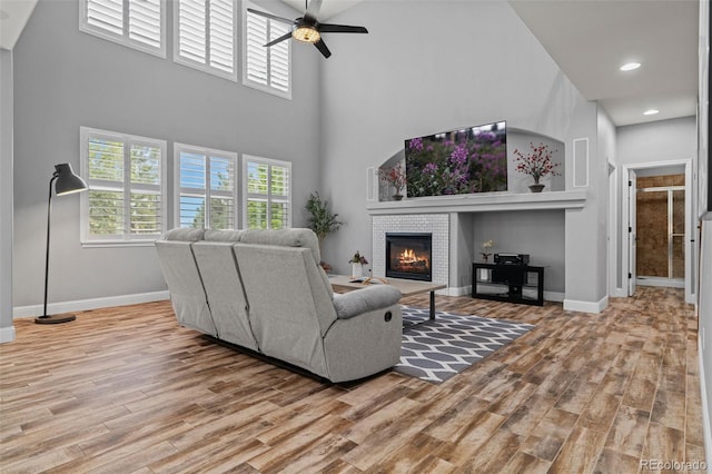 24682 E Ontario Dr, Aurora, CO 80016 - living room with a ceiling fan, wood finished floors, a fireplace, a high ceiling, and baseboards