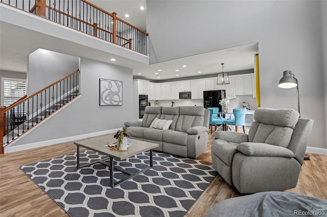 24682 E Ontario Dr, Aurora, CO 80016 - living area featuring a high ceiling, light wood-style flooring, stairs, baseboards, and recessed lighting
