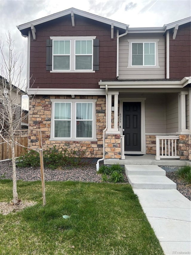 craftsman-style home with a porch, a front lawn, and stone siding