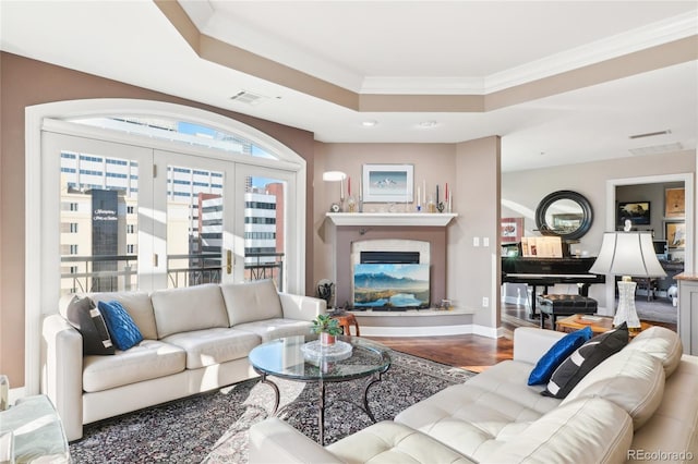 living room with hardwood / wood-style flooring, a raised ceiling, and ornamental molding