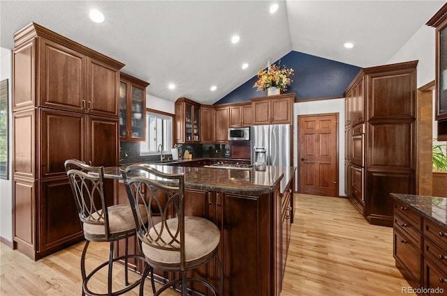 17815 Saddlewood, Monument, CO 80132 - kitchen featuring stainless steel appliances, light wood-type flooring, a kitchen island, decorative backsplash, and lofted ceiling