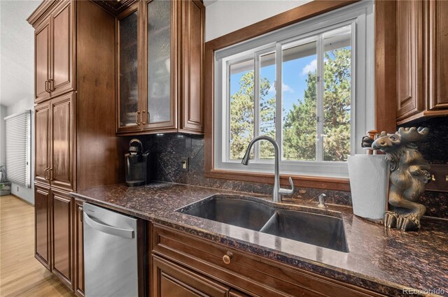 17815 Saddlewood, Monument, CO 80132 - kitchen with stainless steel dishwasher, dark stone counters, glass insert cabinets, and decorative backsplash