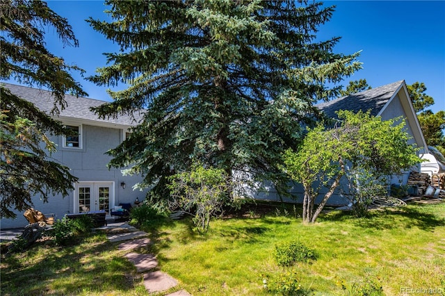 17815 Saddlewood, Monument, CO 80132 - view of side of home featuring french doors, a yard, roof with shingles, and stucco siding