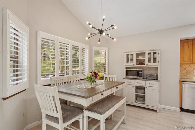 dining space with high vaulted ceiling, light wood-type flooring, and a chandelier