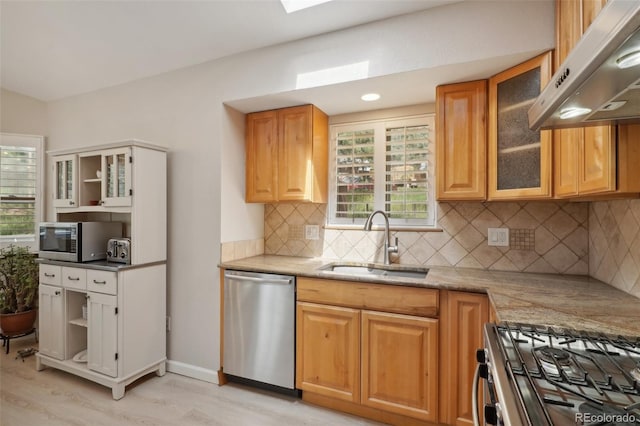 kitchen featuring decorative backsplash, light stone countertops, light hardwood / wood-style floors, stainless steel appliances, and sink