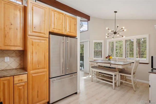 kitchen featuring tasteful backsplash, vaulted ceiling, a healthy amount of sunlight, and stainless steel refrigerator