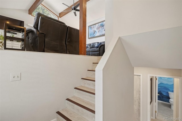 stairs with ceiling fan, wood-type flooring, and vaulted ceiling with beams