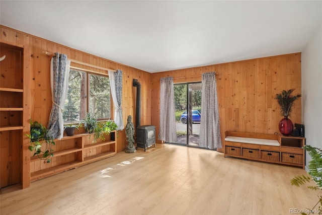 miscellaneous room with a wood stove, wooden walls, and light hardwood / wood-style floors