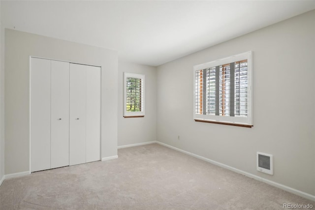 unfurnished bedroom with light carpet and a closet