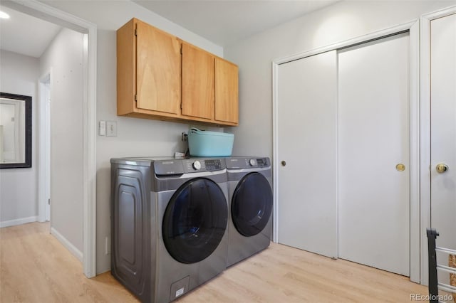 laundry area featuring cabinets, light wood-type flooring, and washer and dryer