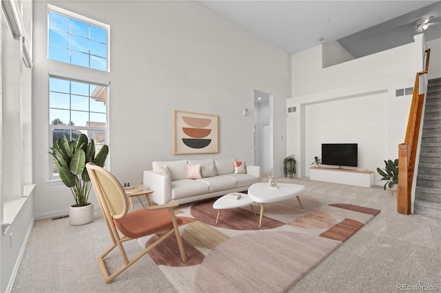 living room with a towering ceiling and light colored carpet