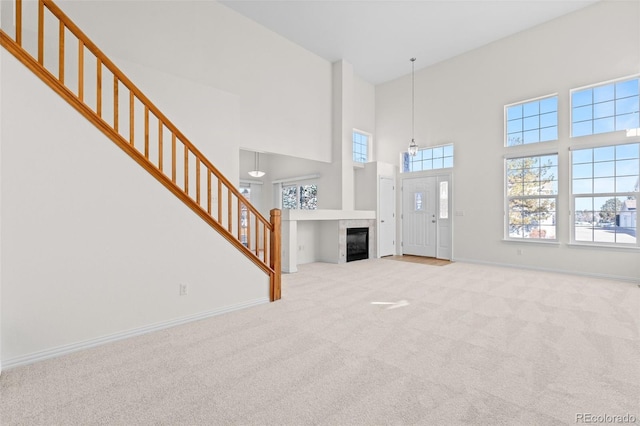 unfurnished living room with light carpet, a fireplace, and a high ceiling