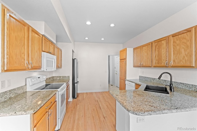 kitchen with sink, white appliances, light stone countertops, and kitchen peninsula