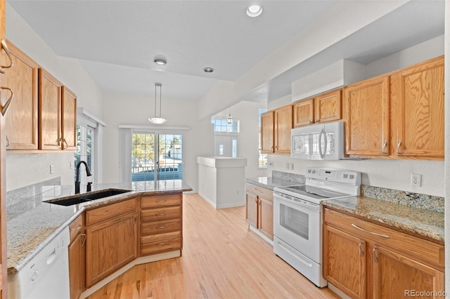 kitchen featuring sink, light stone counters, decorative light fixtures, white appliances, and light hardwood / wood-style floors