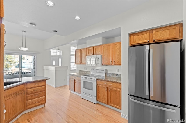 kitchen featuring pendant lighting, a wealth of natural light, white appliances, and light hardwood / wood-style flooring