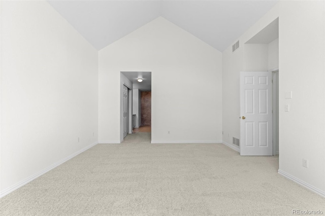 carpeted spare room featuring high vaulted ceiling