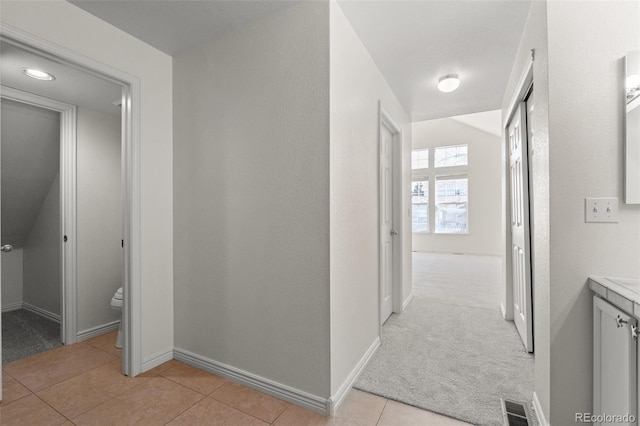 hallway with lofted ceiling and light colored carpet