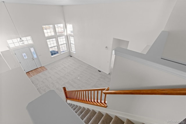 staircase featuring carpet flooring and a high ceiling