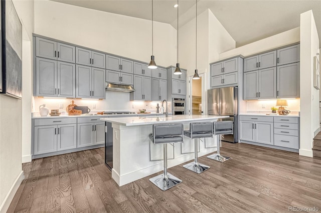 kitchen featuring pendant lighting, high vaulted ceiling, a kitchen breakfast bar, gray cabinets, and dark hardwood / wood-style flooring