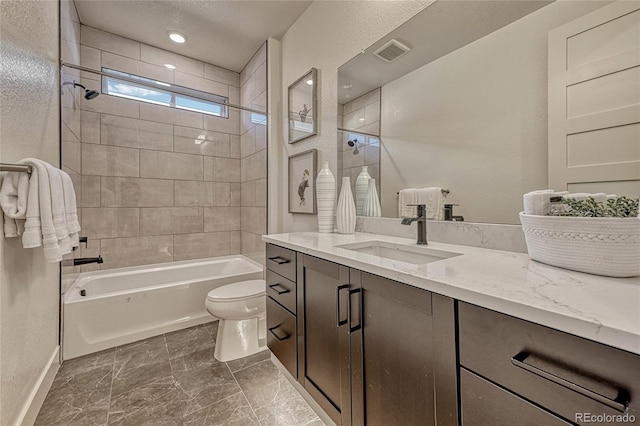 full bathroom featuring vanity, tiled shower / bath combo, and toilet