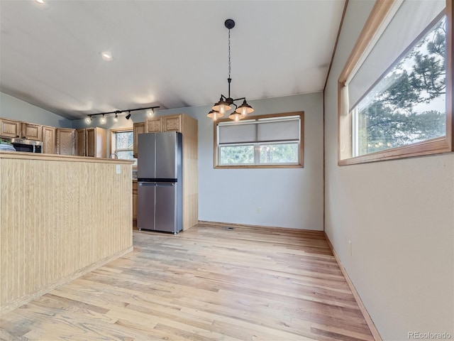 kitchen with an inviting chandelier, light wood-type flooring, track lighting, stainless steel appliances, and lofted ceiling