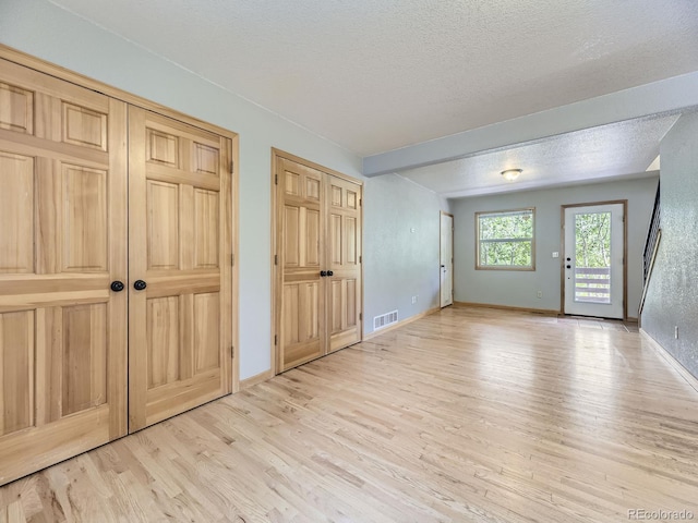 interior space with a textured ceiling and light hardwood / wood-style flooring