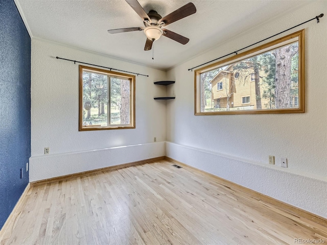 unfurnished room with ceiling fan, light wood-type flooring, and a textured ceiling