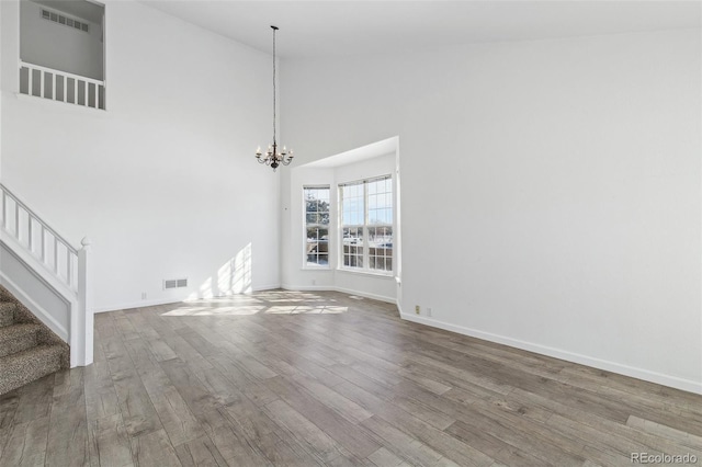 unfurnished living room featuring high vaulted ceiling, a chandelier, and hardwood / wood-style floors