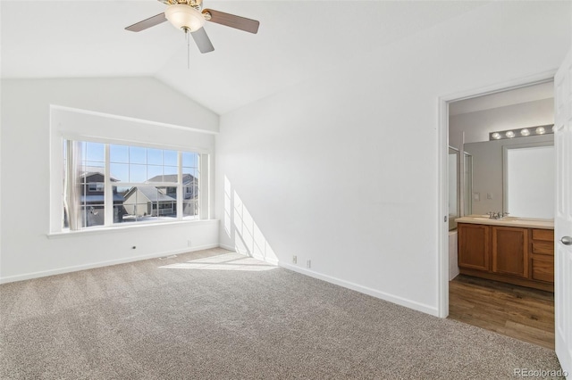 unfurnished bedroom with ensuite bathroom, carpet, vaulted ceiling, and sink