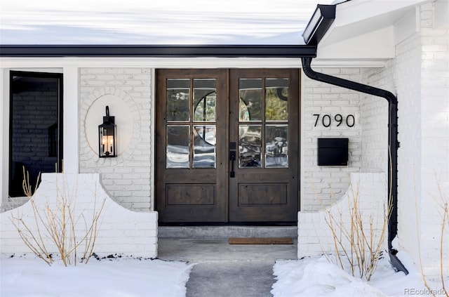 snow covered property entrance with french doors