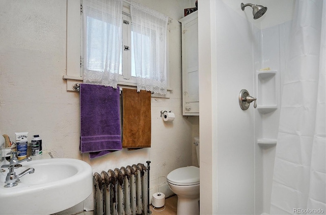 bathroom featuring a shower with shower curtain, toilet, radiator heating unit, and sink