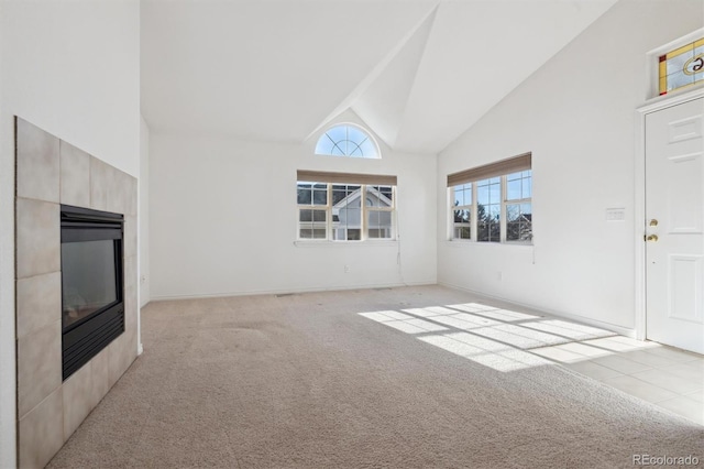 unfurnished living room with light colored carpet, a fireplace, and high vaulted ceiling