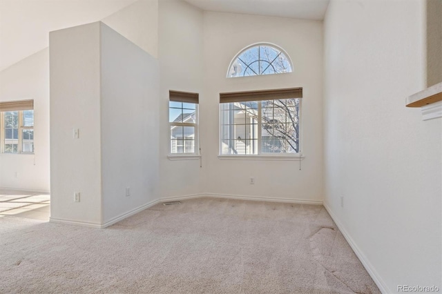 spare room with high vaulted ceiling and light colored carpet