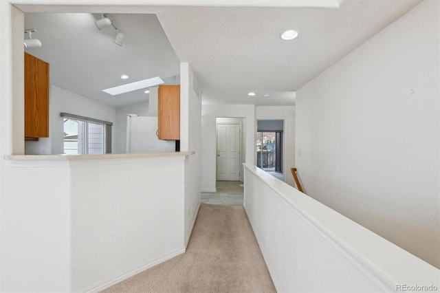 hallway with light carpet and a skylight