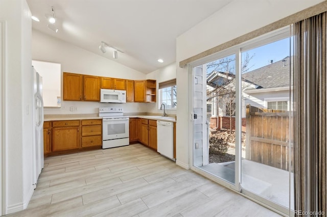 kitchen with white appliances, lofted ceiling, and sink